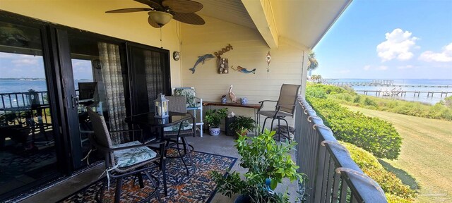 balcony with ceiling fan and a water view