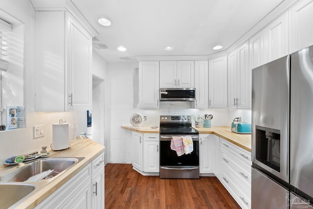 kitchen with appliances with stainless steel finishes, white cabinetry, and dark hardwood / wood-style floors