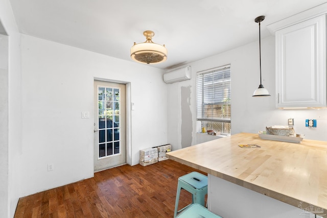 kitchen featuring pendant lighting, dark hardwood / wood-style floors, a wall mounted AC, and plenty of natural light