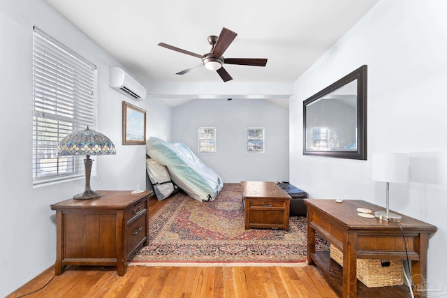 bedroom featuring ceiling fan, light hardwood / wood-style flooring, and a wall unit AC