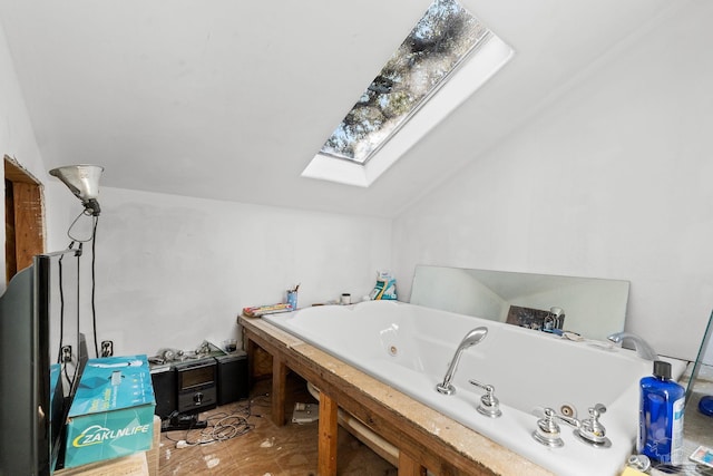 bathroom with a bathing tub and vaulted ceiling with skylight