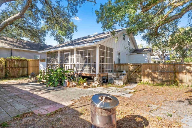 rear view of house with a fire pit, a patio, and a sunroom