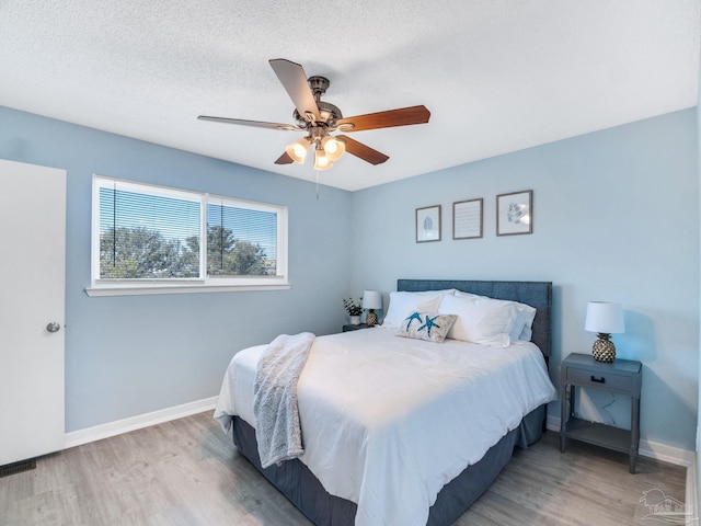 bedroom featuring ceiling fan, light hardwood / wood-style flooring, and a textured ceiling