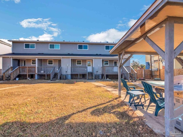 back of house with a wooden deck and a lawn