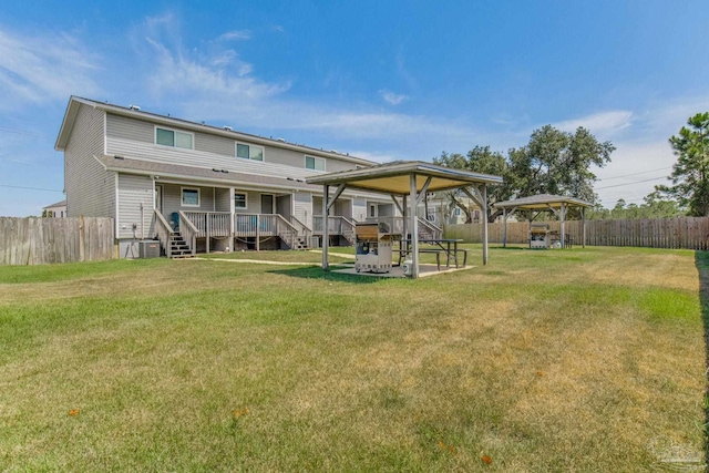 rear view of property with a gazebo, a deck, and a lawn