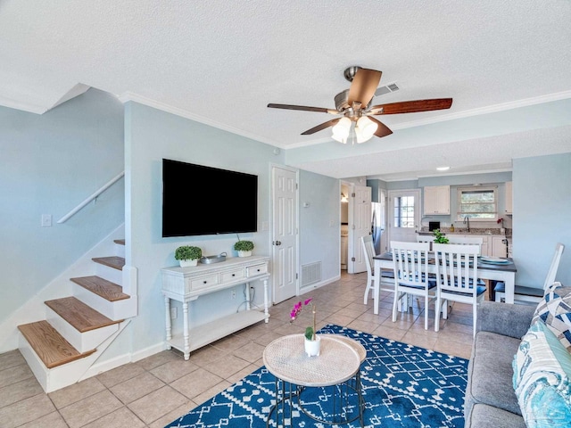 tiled living room with ceiling fan, crown molding, and a textured ceiling