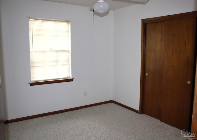 unfurnished bedroom featuring ceiling fan, light colored carpet, and a closet