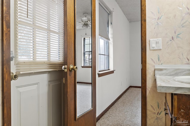 doorway to outside featuring ceiling fan, light carpet, and a textured ceiling