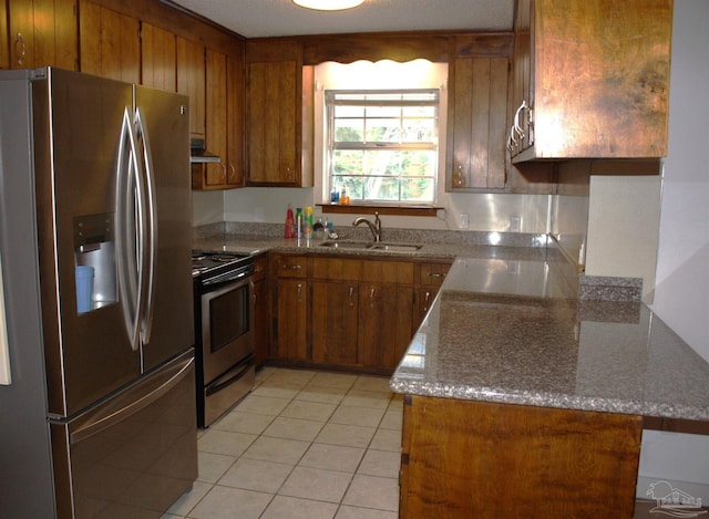 kitchen with light stone countertops, light tile patterned flooring, appliances with stainless steel finishes, and sink