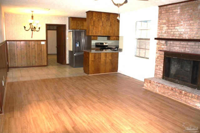 kitchen featuring decorative light fixtures, light hardwood / wood-style flooring, stainless steel appliances, and kitchen peninsula