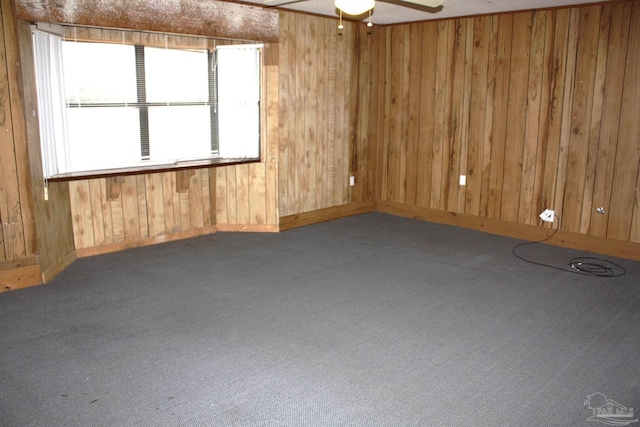 carpeted spare room featuring ceiling fan and wooden walls