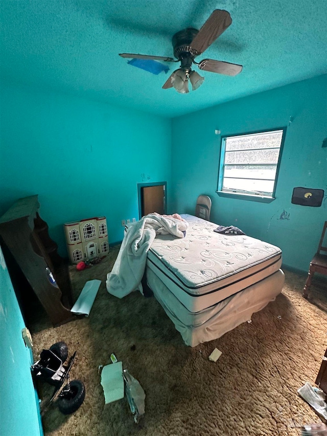 bedroom featuring ceiling fan, carpet floors, and a textured ceiling