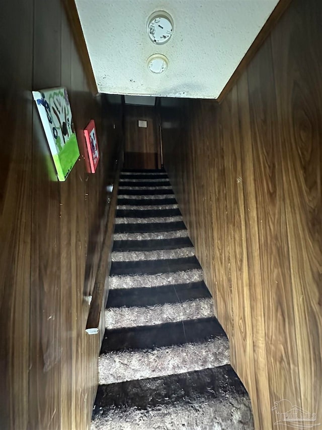 stairway featuring wood walls and a textured ceiling