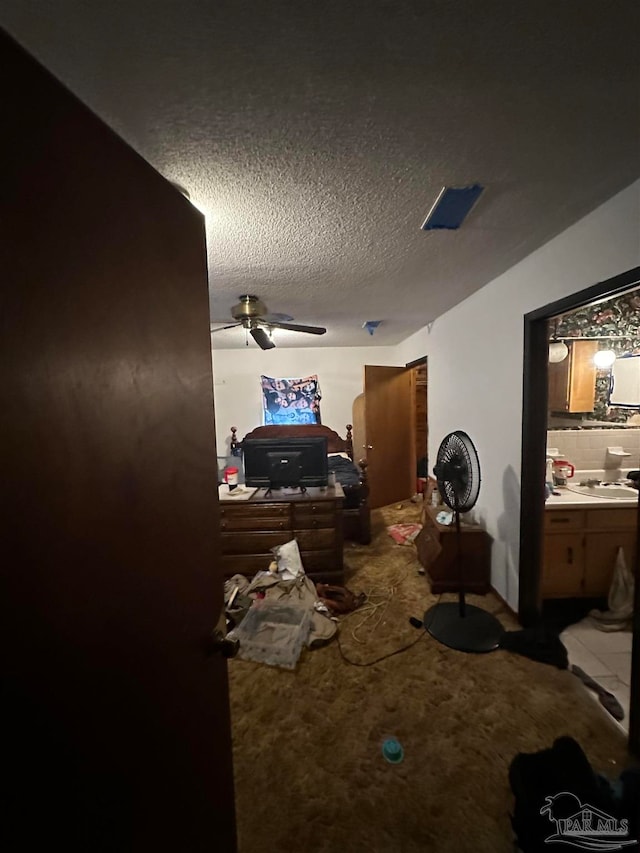 bedroom with a textured ceiling, ceiling fan, and ensuite bath