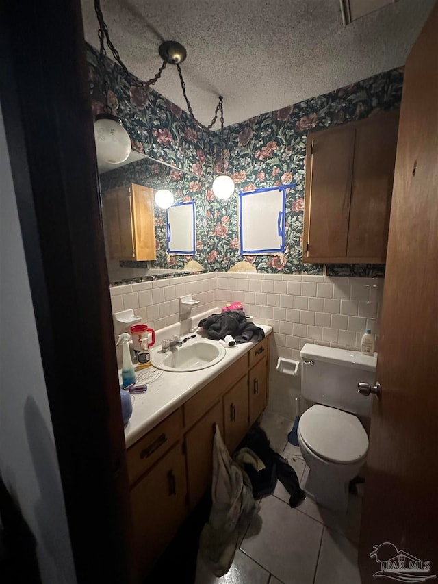 bathroom with toilet, vanity, a textured ceiling, backsplash, and tile walls