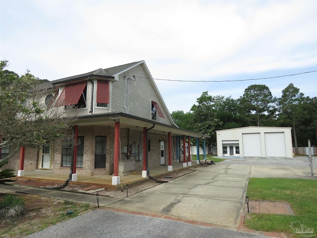 view of side of property featuring a porch, a garage, brick siding, and an outdoor structure