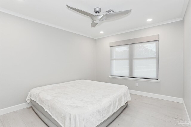 bedroom with light wood-style floors, baseboards, crown molding, and visible vents
