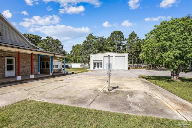 view of patio / terrace with a garage, fence, an outbuilding, and driveway
