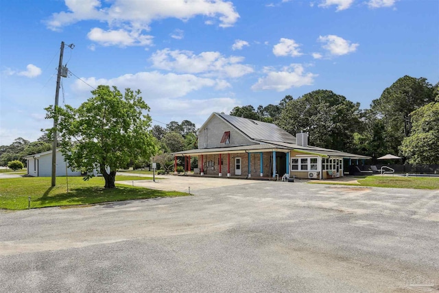 country-style home with a porch, driveway, a chimney, and a front yard