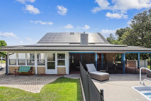 rear view of property with a shingled roof, roof mounted solar panels, and a patio area