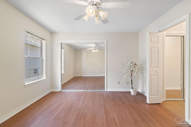 spare room with a textured ceiling, light wood-type flooring, and ceiling fan