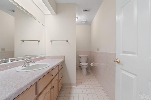 bathroom featuring vanity, a textured ceiling, tile walls, tile patterned flooring, and toilet