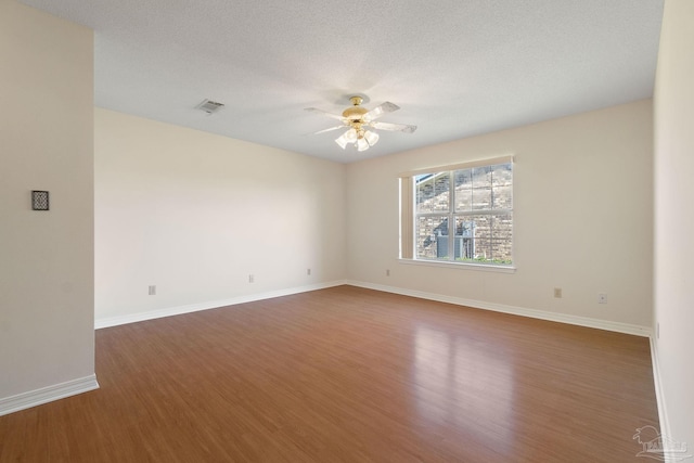 empty room featuring a textured ceiling, dark hardwood / wood-style floors, and ceiling fan