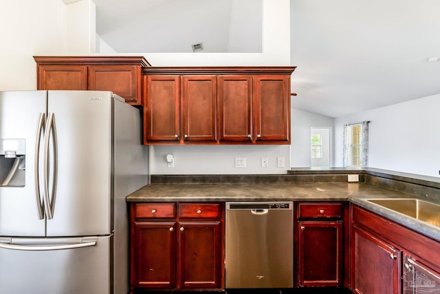 11532 Aruba Dr, Pensacola, FL 32506 - kitchen with lofted ceiling, dark countertops, reddish brown cabinets, a sink, and appliances with stainless steel finishes
