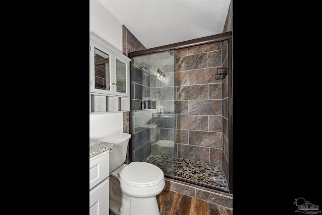 bathroom with hardwood / wood-style flooring, vanity, toilet, and a shower with shower door