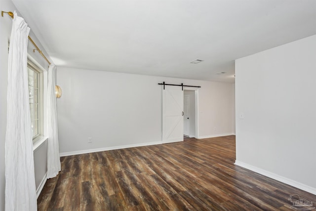 unfurnished room with a barn door and dark hardwood / wood-style flooring