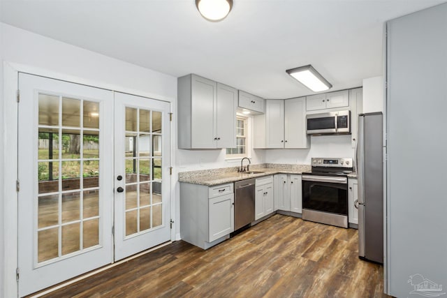 kitchen with light stone countertops, appliances with stainless steel finishes, french doors, sink, and dark hardwood / wood-style floors