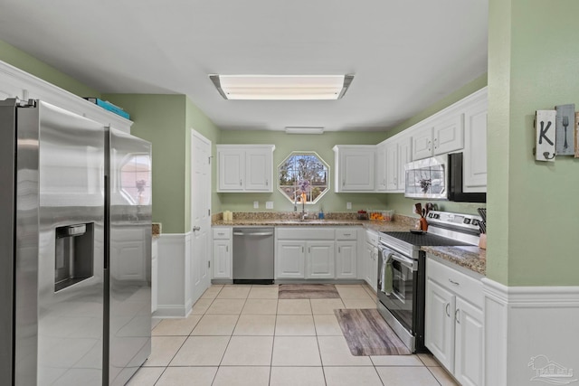 kitchen with white cabinetry, appliances with stainless steel finishes, and dark stone counters