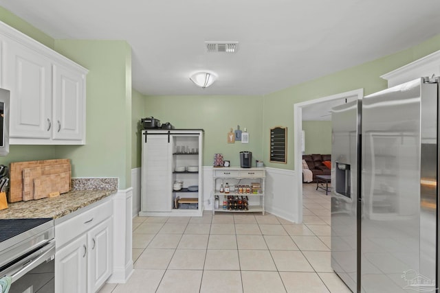 kitchen with stainless steel refrigerator with ice dispenser, visible vents, light tile patterned flooring, white cabinetry, and light stone countertops