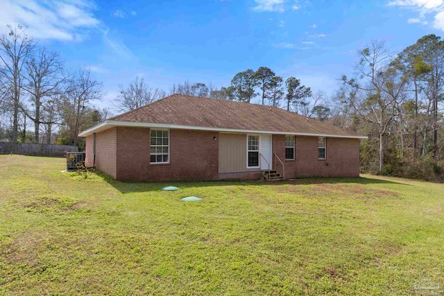 back of house with entry steps, brick siding, and a yard