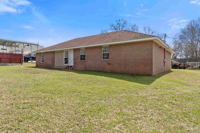 back of property with entry steps, brick siding, and a yard