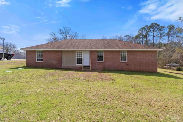 back of house featuring entry steps, brick siding, and a lawn