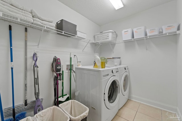 laundry room featuring laundry area, light tile patterned floors, baseboards, washer and clothes dryer, and a textured ceiling