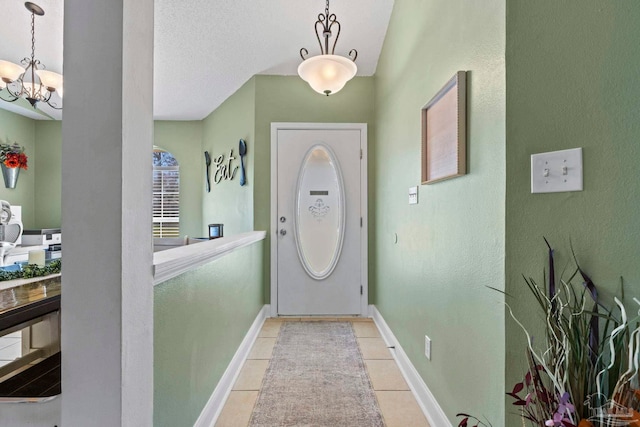 entrance foyer featuring a chandelier, light tile patterned flooring, a textured ceiling, and baseboards