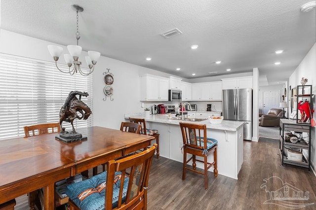 kitchen featuring dark wood-type flooring, kitchen peninsula, stainless steel appliances, sink, and white cabinetry