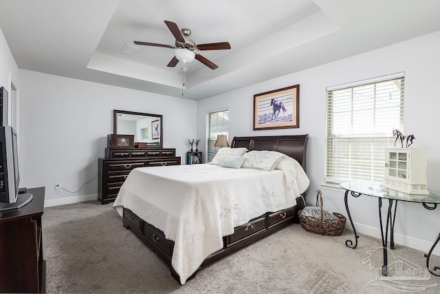 bedroom with ceiling fan, carpet flooring, and a tray ceiling