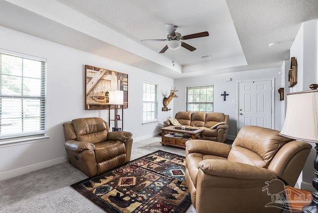 carpeted living room with a textured ceiling, a raised ceiling, and ceiling fan