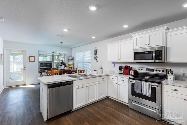 kitchen with white cabinetry, stainless steel appliances, decorative light fixtures, and kitchen peninsula