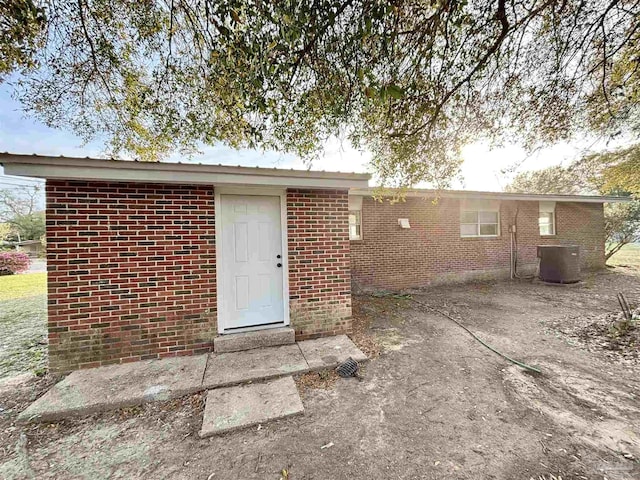 exterior space with brick siding and central AC