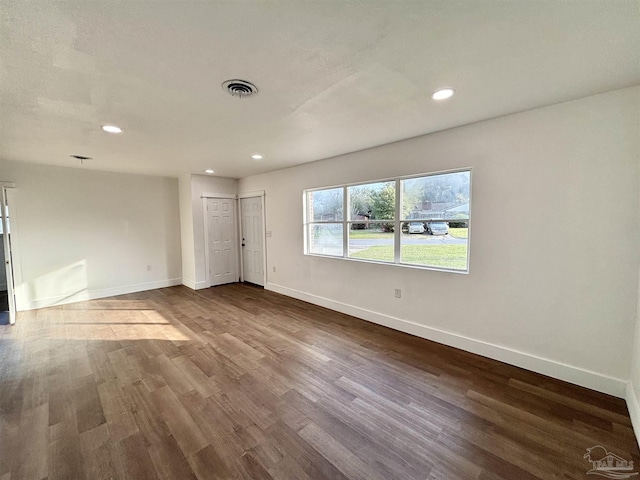 unfurnished room with recessed lighting, visible vents, baseboards, and dark wood finished floors