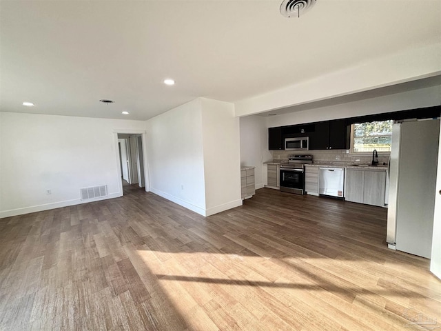 unfurnished living room featuring recessed lighting, wood finished floors, visible vents, and baseboards