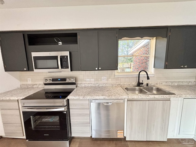 kitchen with tasteful backsplash, stainless steel appliances, light countertops, and a sink