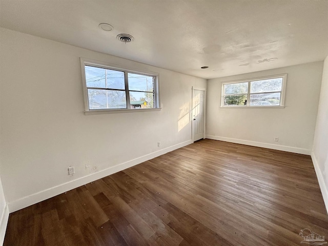 empty room with visible vents, baseboards, and dark wood-type flooring