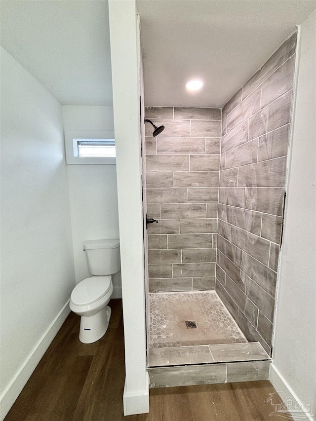 full bath featuring a shower stall, toilet, baseboards, and wood finished floors