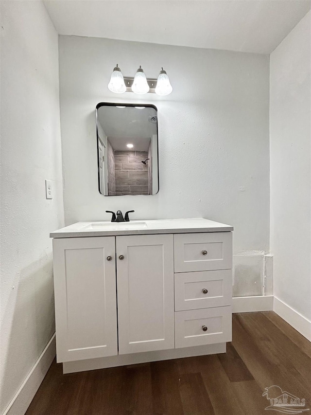 bathroom with baseboards, wood finished floors, and vanity