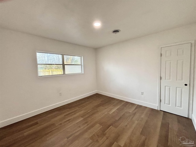 unfurnished room featuring visible vents, baseboards, and dark wood finished floors